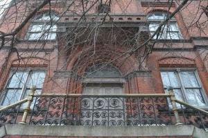 Ornate red brick building with bare branches.