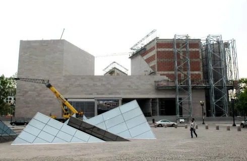Modern building with glass pyramids and crane.