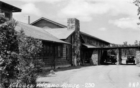 Historic building with vintage cars outside.