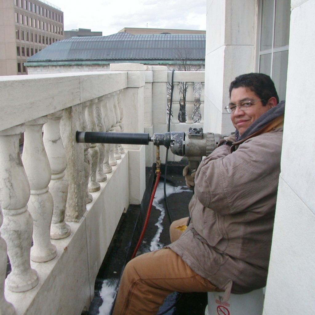 Person sitting on balcony with camera and telescope.