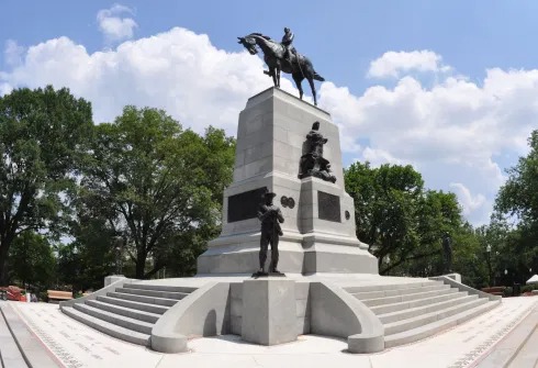 Tall monument with three individuals and a horse